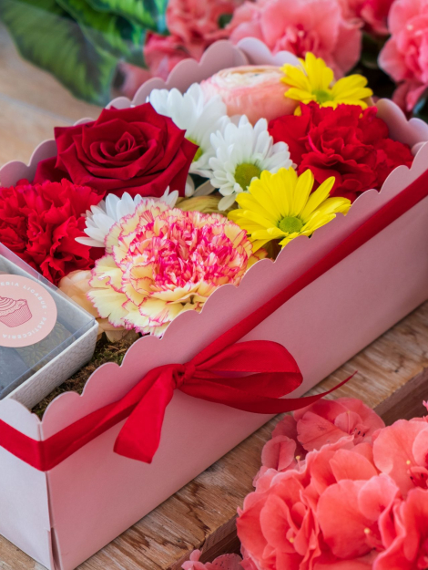 composizione in spugna di fiori freschi e cioccolatini in scatola rosa con coperchio trasparente