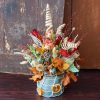 vaso di latta con fiori secchi e frutta disidratata