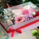 composizione in spugna di fiori freschi e candela in scatola rosa con coperchio trasparente