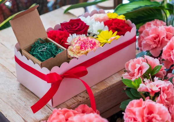 composizione in spugna di fiori freschi e gioiello in argento in scatola rosa con coperchio trasparente